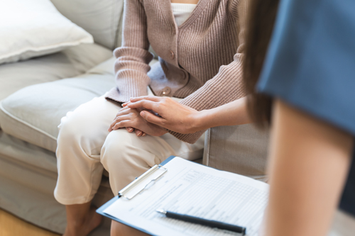 two individuals engaged in a supportive conversation with a clipboard on the table discussing matters related to mental health and well being for a 16 year old
