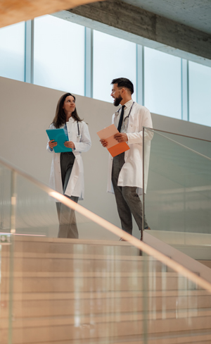 two medical professionals discussing patient files in a modern building with large windows 13 reasons for medical collaboration and teamwork