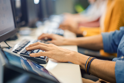 person typing on a keyboard in a computer lab focusing on technology and teamwork