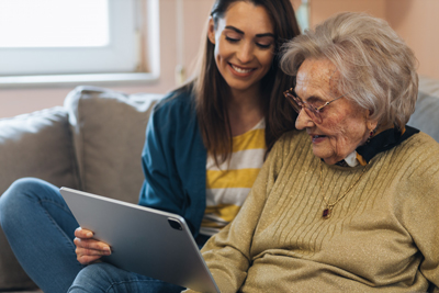 woman and elderly woman sharing a joyful moment looking at a tablet together two generations enjoying technology